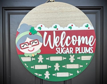 A "Welcome Sugar Plums" Christmas Grandma Baking Cookies-Themed Round Door Hanger/Sign, Choose 2 Color Options, and Available in 2 Sizes