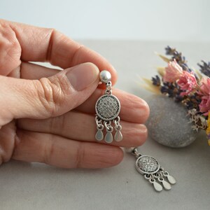 Puede incluir: Un par de pendientes de plata con un dise&ntilde;o redondo de filigrana y detalles en forma de l&aacute;grima.