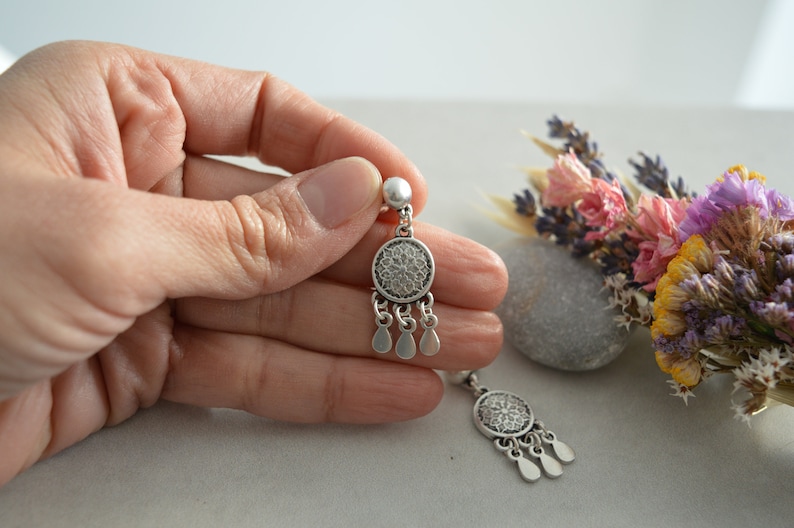 Puede incluir: Un par de pendientes de plata con un dise&ntilde;o redondo de filigrana y detalles en forma de l&aacute;grima.
