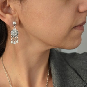 Puede incluir: Pendientes de plata con un dise&ntilde;o redondo y adornado y peque&ntilde;os detalles en forma de l&aacute;grima.