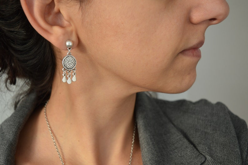Puede incluir: Pendientes de plata con un dise&ntilde;o redondo y adornado y peque&ntilde;os detalles en forma de l&aacute;grima.
