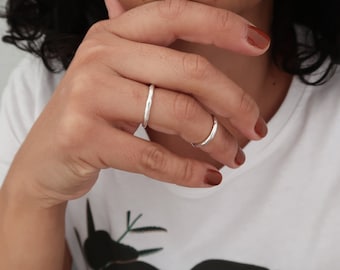 May include: Two silver rings on a person's finger. The rings are simple and delicate, with a smooth, polished finish.