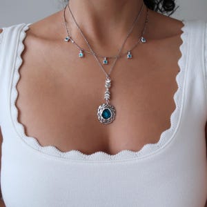 May include: A silver necklace with a turquoise pendant and smaller turquoise stones hanging from the chain.