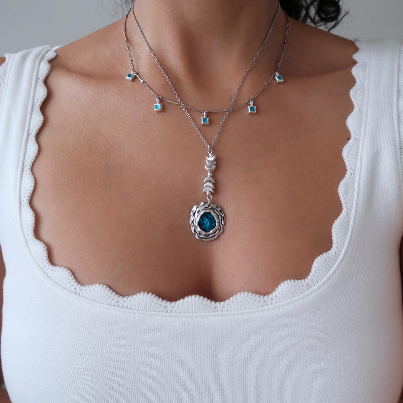 May include: A silver necklace with a turquoise pendant and smaller turquoise stones hanging from the chain.