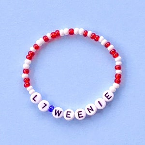 May include: A red and white beaded bracelet with the word "Little Weenie" spelled out in black beads.