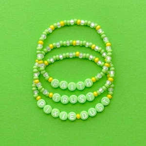 May include: Three green and yellow beaded bracelets with the words "FAITH", "TRUST", and "PIXIE DUST" spelled out in green beads.