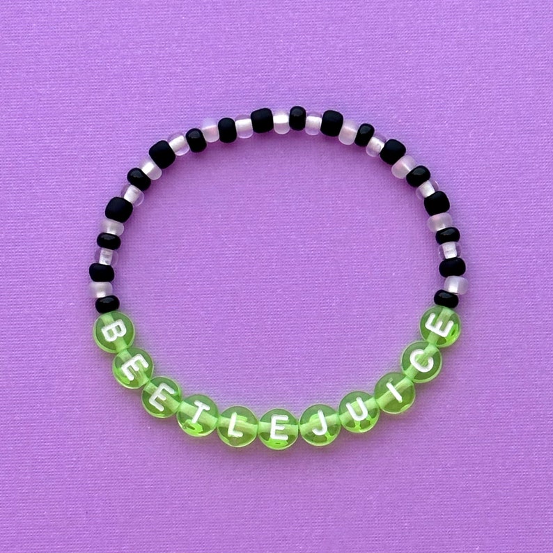 May include: A green and black beaded bracelet with the word "BEETLEJUICE" spelled out in white letters.