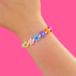 May include: A colorful beaded bracelet with flower-shaped charms in shades of pink, blue, yellow, and purple.