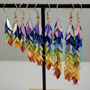K&ouml;nnte beinhalten: Regenbogenfarbene, irisierende Ohrringe mit einem mehrschichtigen Blattdesign. Jeder Ohrring besteht aus mehreren Schichten irisierenden Materials, was einen farbenfrohen und auff&auml;lligen Effekt erzeugt.