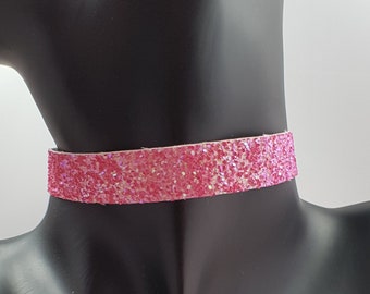 Op de afbeelding: Een roze glitter choker ketting op een zwart mannequin.