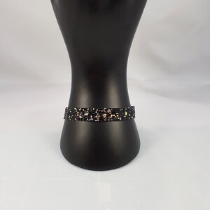 May include: A black bracelet with gold and pink glitter.