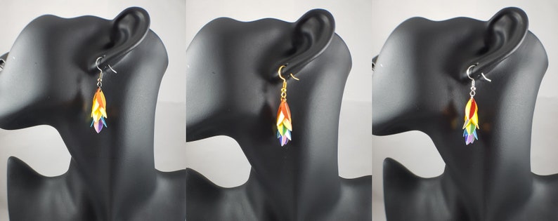 May include: Rainbow colored dangle earrings with a layered flower design. The earrings are on a mannequin head.