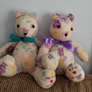 May include: Two handmade teddy bears with floral fabric, each with a ribbon around the neck. One has a teal ribbon, the other a purple ribbon. The bears have embroidered details and personalized text on their feet, including dates and names.