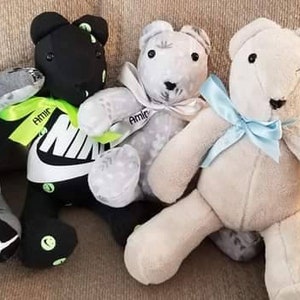 K&ouml;nnte beinhalten: Vier handgefertigte Teddyb&auml;ren in verschiedenen Farben, darunter Grau, Schwarz und Wei&szlig;. Die B&auml;ren haben Schleifen und B&auml;nder, und einige zeigen Nike-Logos und Details der Marke Jordan. Sie sitzen auf einem neutralfarbenen Sofa.
