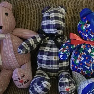 May include: Three handmade teddy bears with unique fabric patterns. One is pink striped, another is black and white plaid, and the third is blue with floral designs. Each bear has a ribbon and embroidered details, including dates and names.