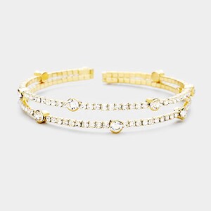 May include: A gold-tone double-row bangle bracelet with clear crystal accents.