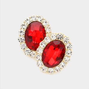 May include: A pair of gold tone earrings with red oval-shaped stones surrounded by clear rhinestones.