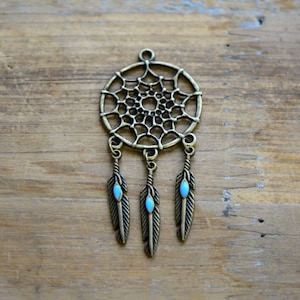 May include: A bronze dreamcatcher pendant with three feathers, each with a turquoise stone at the end.