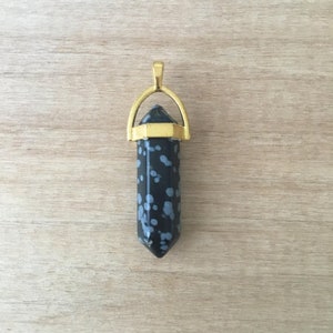 以下が含まれることがあります： 黒と白の雪片オパールのクリスタルポイントを特徴とする金色のペンダント