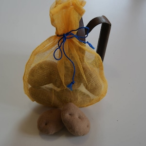 Peut inclure: Un sac en filet jaune rempli de pommes de terre, attaché avec une ficelle bleue. Quatre pommes de terre sont posées à l'extérieur du sac.