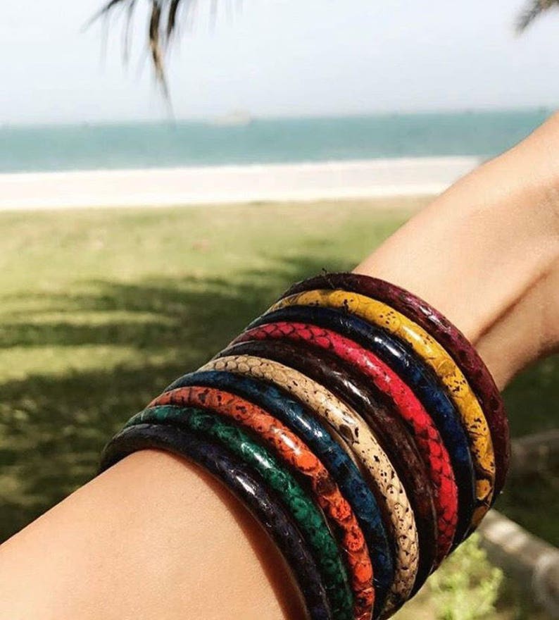 May include: A stack of colorful bracelets with a snakeskin pattern. The bracelets are made of leather and are worn on a person's wrist.