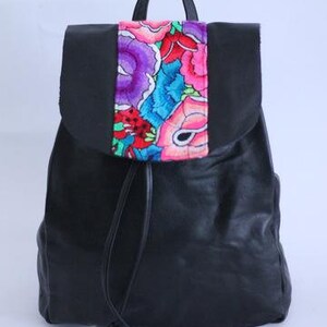Könnte beinhalten: Schwarzer Lederrucksack mit einem bunten, gestickten Blumenmuster auf der vorderen Klappe.