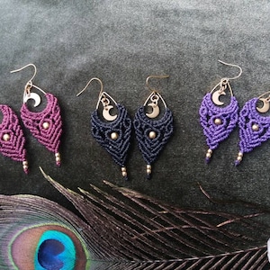 May include: Three pairs of handmade macrame earrings with gold crescent moon charms. The earrings are in shades of purple, black, and dark purple.