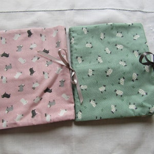 May include: Two fabric gift bags with a sheep pattern. One bag is pink with black sheep and the other is green with white sheep.