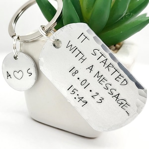 May include: Silver keyring with a tag that reads "It started with a message... 18.01.23 15:49". A smaller charm with the letters "A ♥ S" is attached to the keyring.