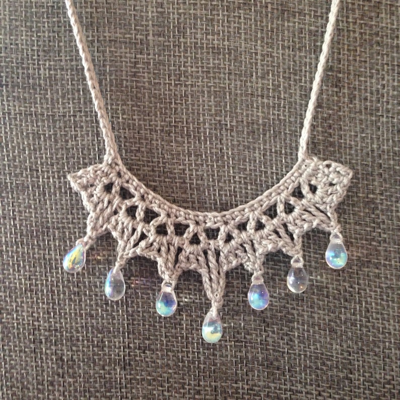 May include: A crocheted necklace with a delicate, lacy design and iridescent teardrop beads.