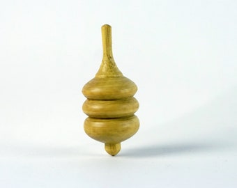May include: A wooden spinning top with a rounded, bulbous shape and three stacked rings. The top is light brown in color and has a smooth, polished finish.