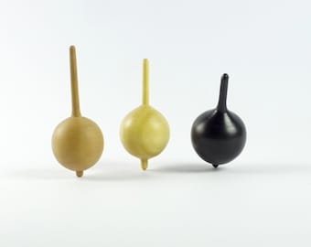 May include: Three wooden spinning tops, one is natural wood, one is light yellow wood, and one is black.