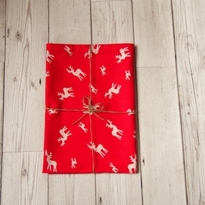 May include: Red wrapping paper with a white reindeer pattern, tied with twine.