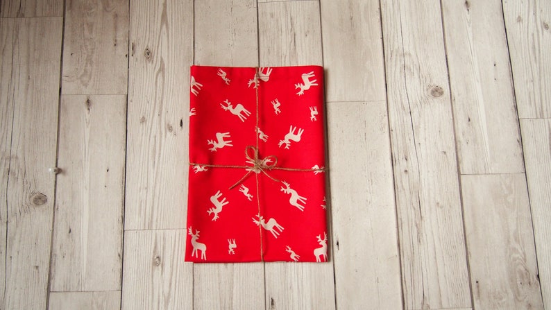 May include: Red wrapping paper with a white reindeer pattern, tied with twine.