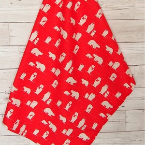 May include: Red fabric with a repeating pattern of white polar bears wearing red scarves. The bears are in various poses, some with their cubs. The fabric is hanging against a light wood background.