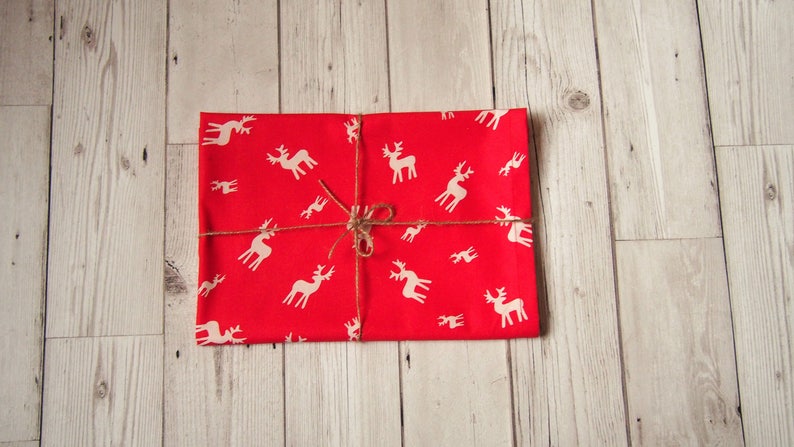 May include: A red gift box wrapped in paper with a white reindeer pattern and tied with twine.