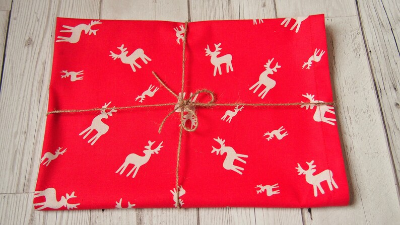 May include: Red wrapping paper with a white reindeer pattern. The paper is tied with twine.