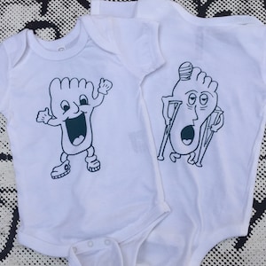 May include: Two white baby onesies with a cartoon foot design. One onesie shows a happy foot with arms and legs, while the other shows a foot with a bandage and crutches.