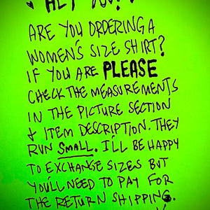 May include: A green handwritten note with the text "HEY YOU! ARE YOU ORDERING A WOMEN'S SIZE SHIRT? IF YOU ARE PLEASE CHECK THE MEASUREMENTS IN THE PICTURE SECTION + ITEM DESCRIPTION. THEY RUN SMALL. ILL BE HAPPY TO EXCHANGE SIZES BUT YOU'LL NEED TO PAY FOR THE RETURN SHIPPING. THANK YOU!"