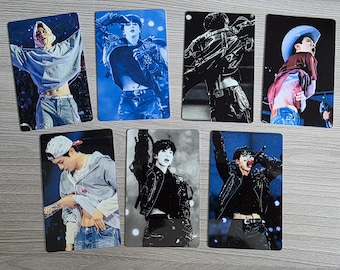 May include: A collection of seven rectangular photo cards featuring images of a performer in various poses. The cards showcase the performer in different outfits, including a hoodie, jacket, and cowboy hat, with vibrant stage lighting.