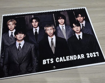 May include: A spiral-bound wall calendar featuring a group photograph of seven individuals wearing formal dark suits and ties. The text BTS CALENDAR 2027 is printed in white capital letters at the bottom right corner of the cover page.