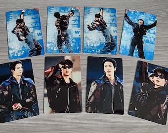 May include: A collection of seven rectangular photo cards featuring a performer in a black jacket and dark pants. Four cards show the performer in dynamic stage poses, while three cards show close-up portraits of the performer wearing sunglasses.