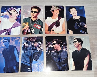 May include: Eight rectangular photo cards featuring a person performing on stage in various outfits, including white and black shirts, a green sports jersey, and dark jackets, with some images showing the person wearing sunglasses and holding a microphone.