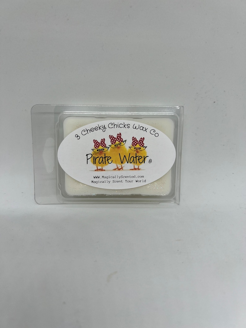 May include: A white wax melt with a label that says "3 Cheeky Chicks Wax Co. Pirate Water" with a cartoon image of three chicks wearing red and white polka dot bows and sunglasses. The label also includes the website address "www.MagicallyScented.com" and the tagline "Magically Scent Your World."