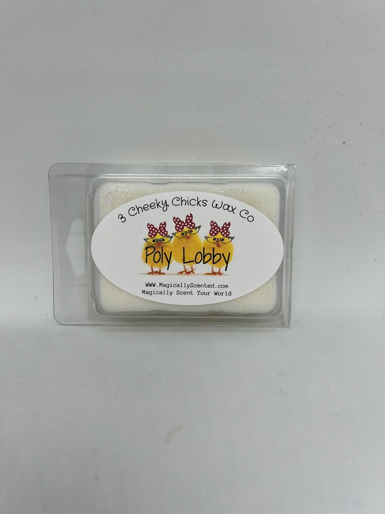 Peut inclure: Un fondant de cire blanc avec une &eacute;tiquette qui dit "3 Cheeky Chicks Wax Co. Poly Lobby" avec une image de dessin anim&eacute; de trois poussins portant des lunettes et des n&oelig;uds rouges. L'&eacute;tiquette dit &eacute;galement "www.MagicallyScented.com Magically Scent Your World."