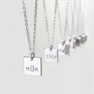 May include: A set of silver necklaces with square pendants, each engraved with different initials. The initials on the pendants are MBK, CHJ, and others.