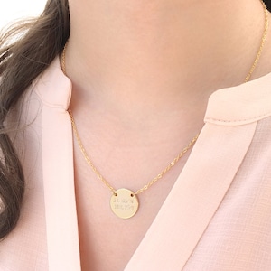 Puede incluir: Un collar de cadena de oro con un colgante redondo con coordenadas grabadas.