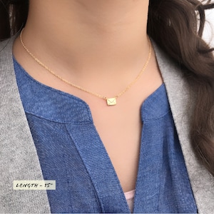 May include: A gold chain necklace with a small gold envelope pendant. The necklace is 15 inches long.  LENGTH - 15"