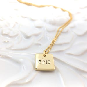 May include: Gold necklace with a square pendant engraved with the initials "GMS".