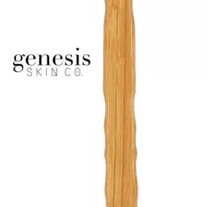 Puede incluir: Un cepillo corporal de madera de mango largo con cerdas naturales. El cepillo tiene un lazo de cuerda en el extremo del mango. El texto "genesis skin co." está impreso en el mango.